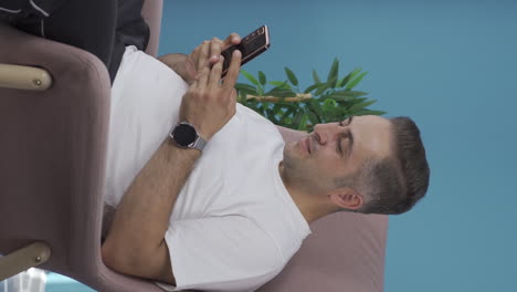 Vertical-video-of-Man-texting-with-happy-expression.